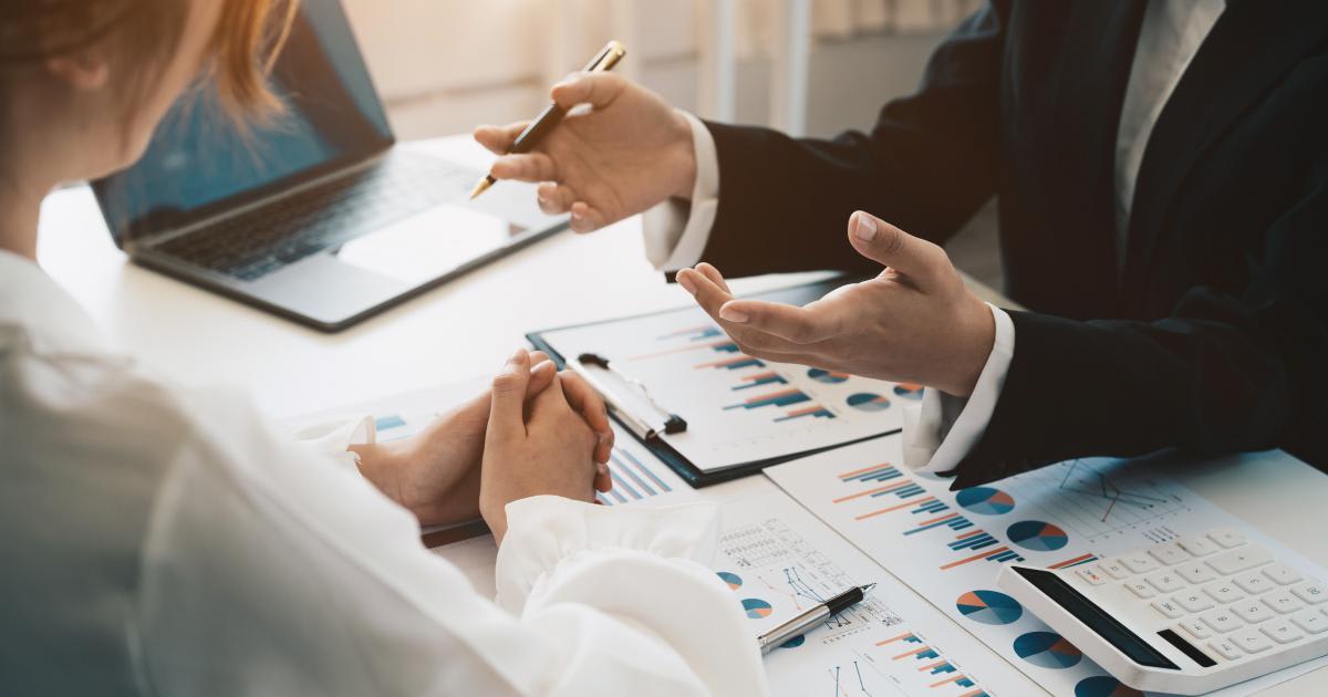 Two people working at desk together looking at graphs