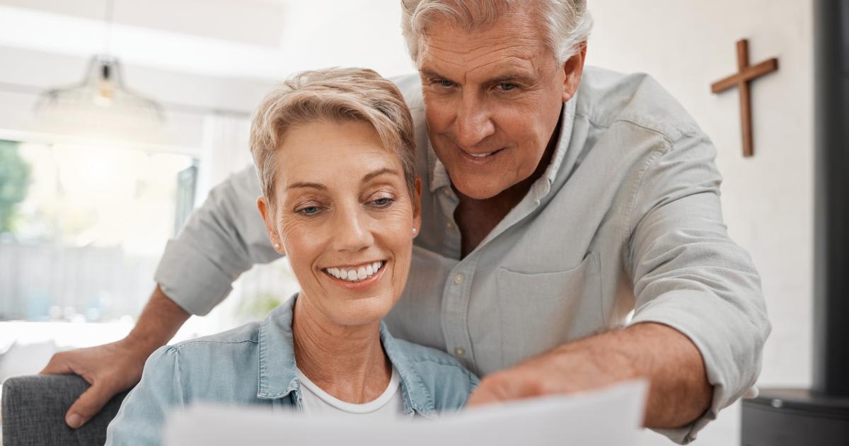 Senior couple smiling while reviewing dividend investment statements together at home
