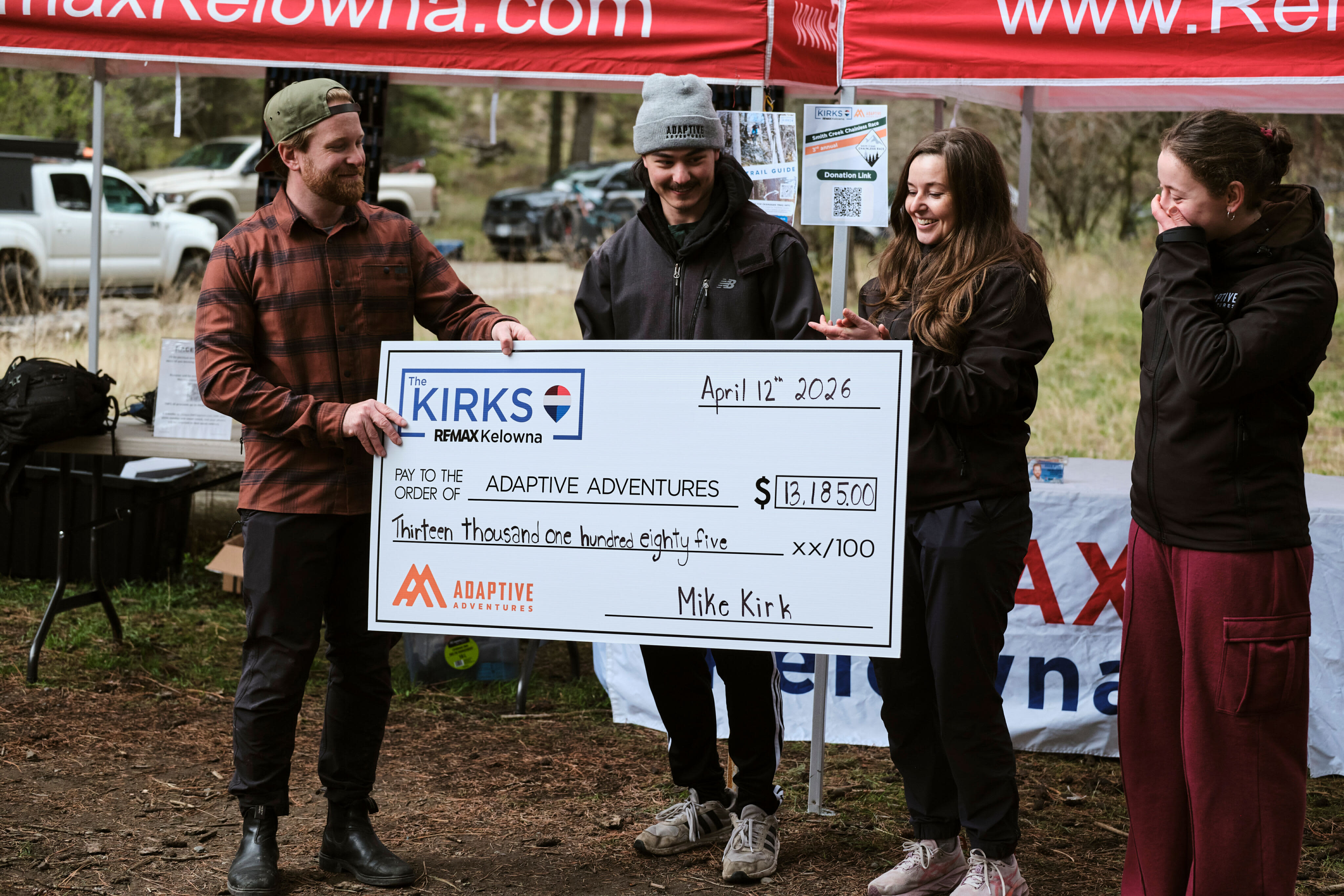 Mike Kirk presents a $13,185 cheque to Adaptive Adventures at the Smith Creek Chainless Race, April 12, 2026. Photo: Chris Skomorowski / @Typetwophoto