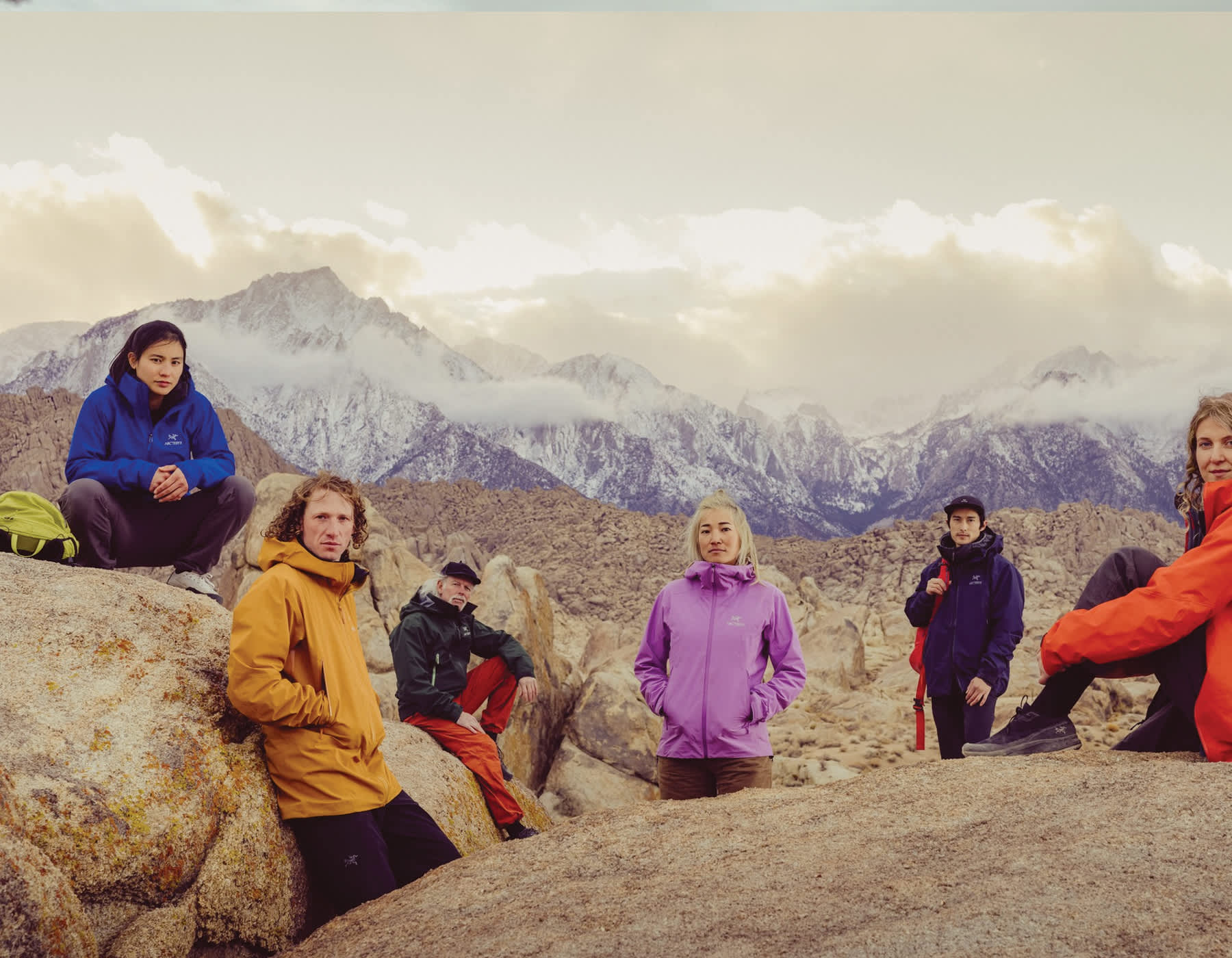 Arc’teryx ambassadors. A group of Arc'teryx ambassadors wearing jackets, sitting on rocks with mountains in the background