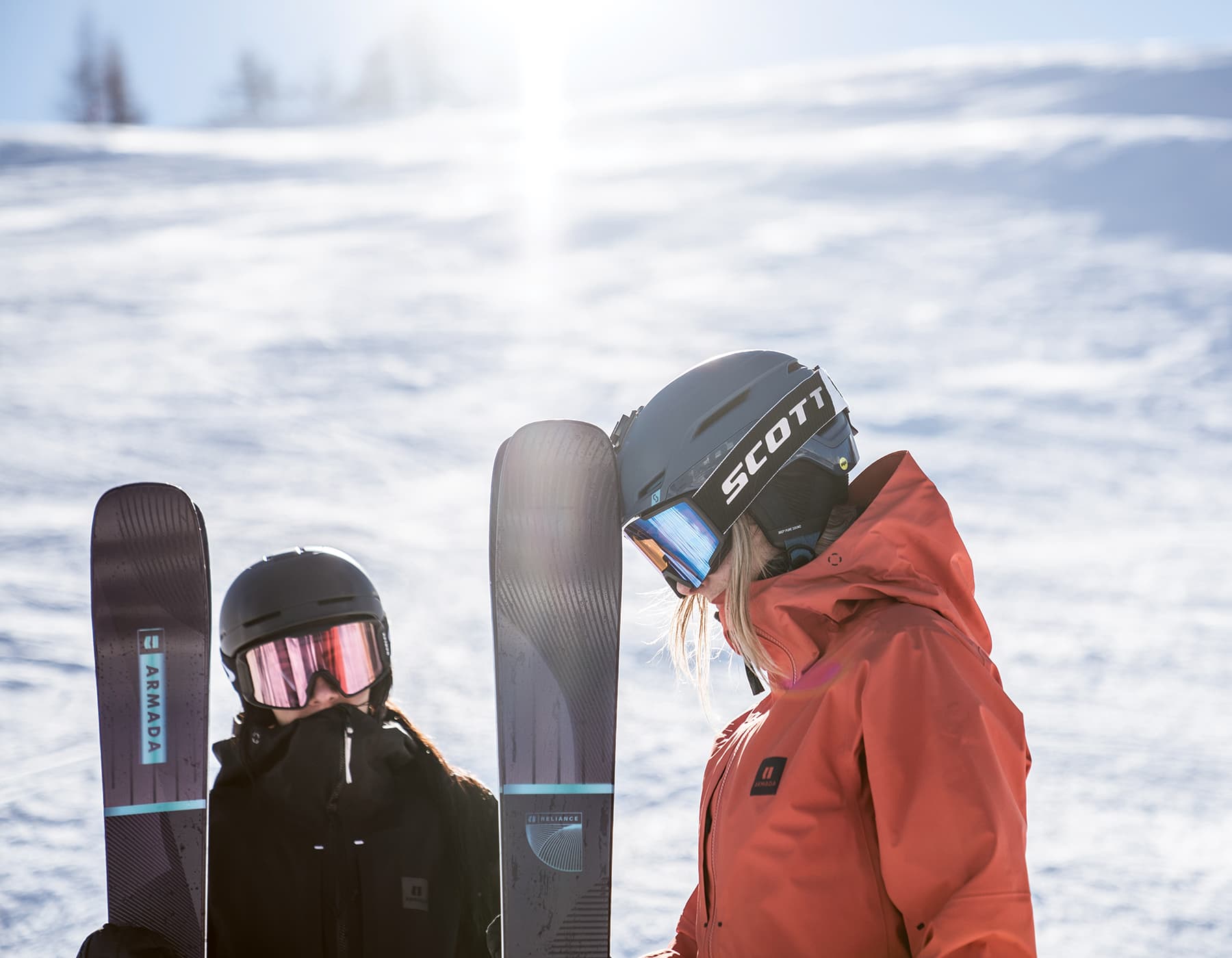 Alpine Initiatives. Two skiers wearing Armada winter shell jackets holding Armada skis