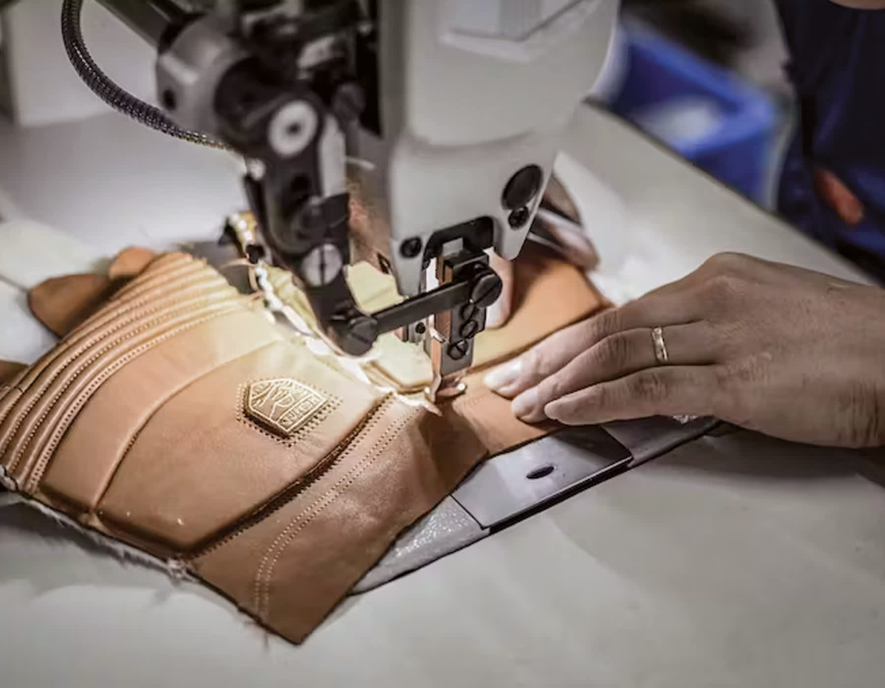 A hang using an industrial sewing machine sewing the cuff onto a pair of camel leather Hestra gloves.