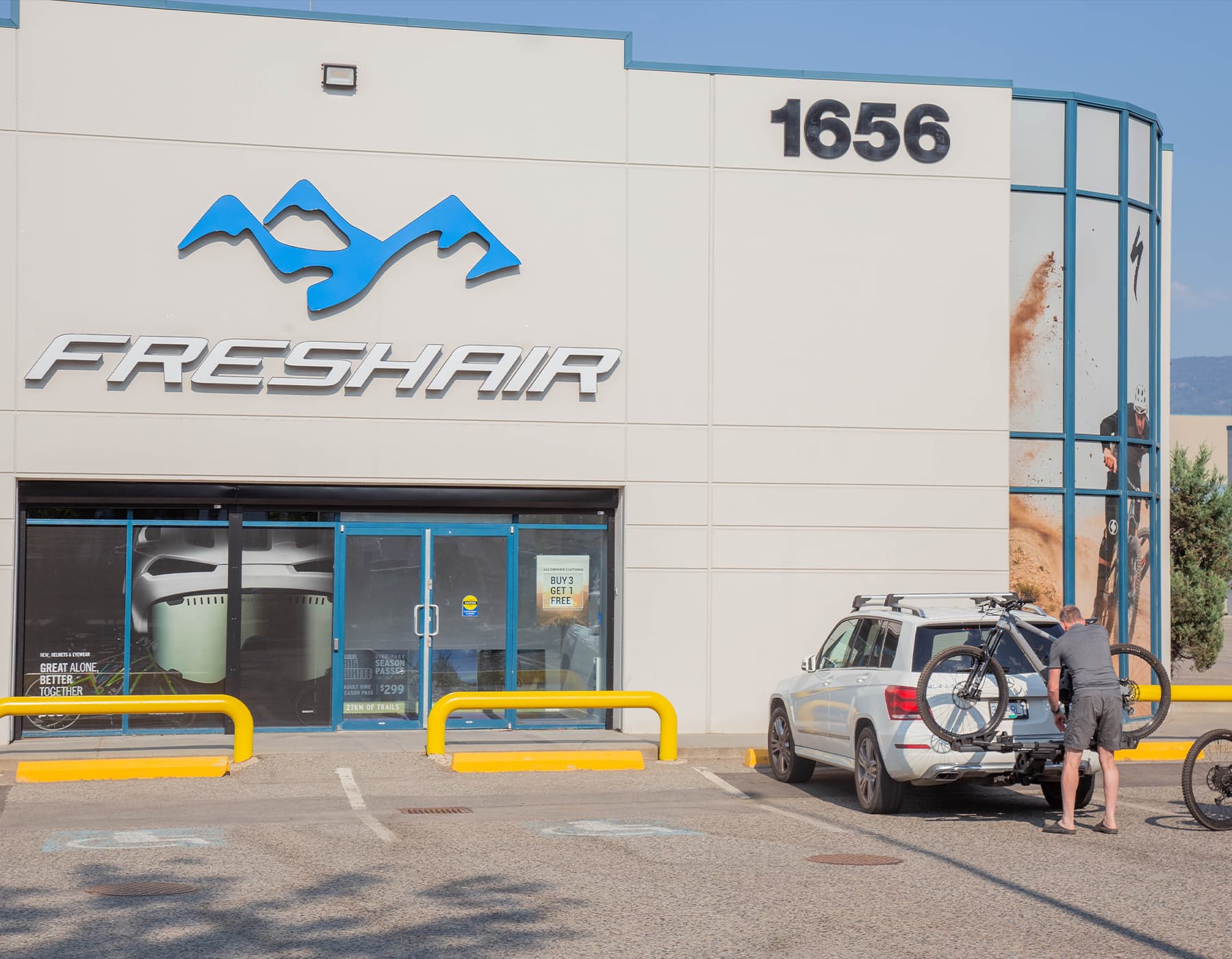 Man preparing to transport new mountain bike on Thule rack outside Fresh Air store in Kelowna BC