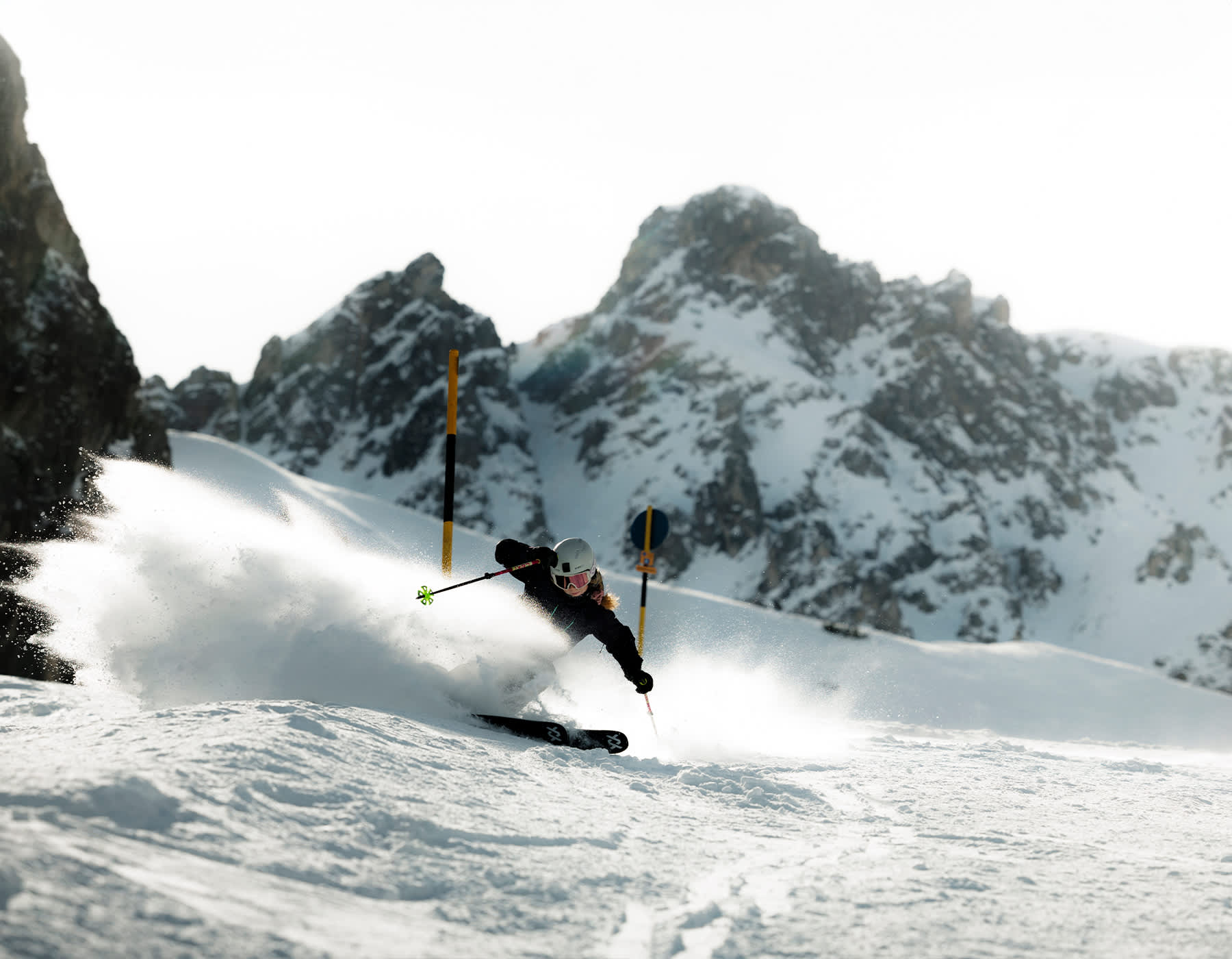 Völkl powder skis in action as a skier glides down a powder-covered mountain, surrounded by fresh winter snow