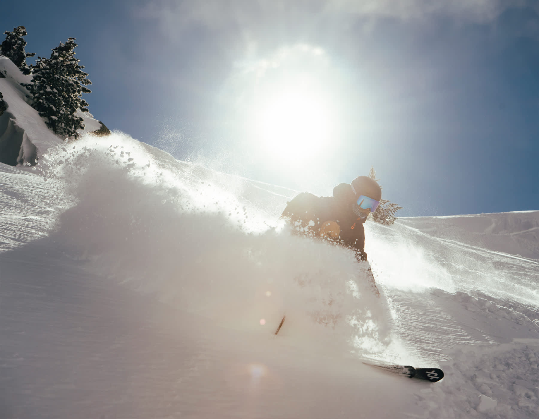  Action shot of a skier navigating deep snow on Völkl powder skis, showcasing control and performance on a mountain slope
