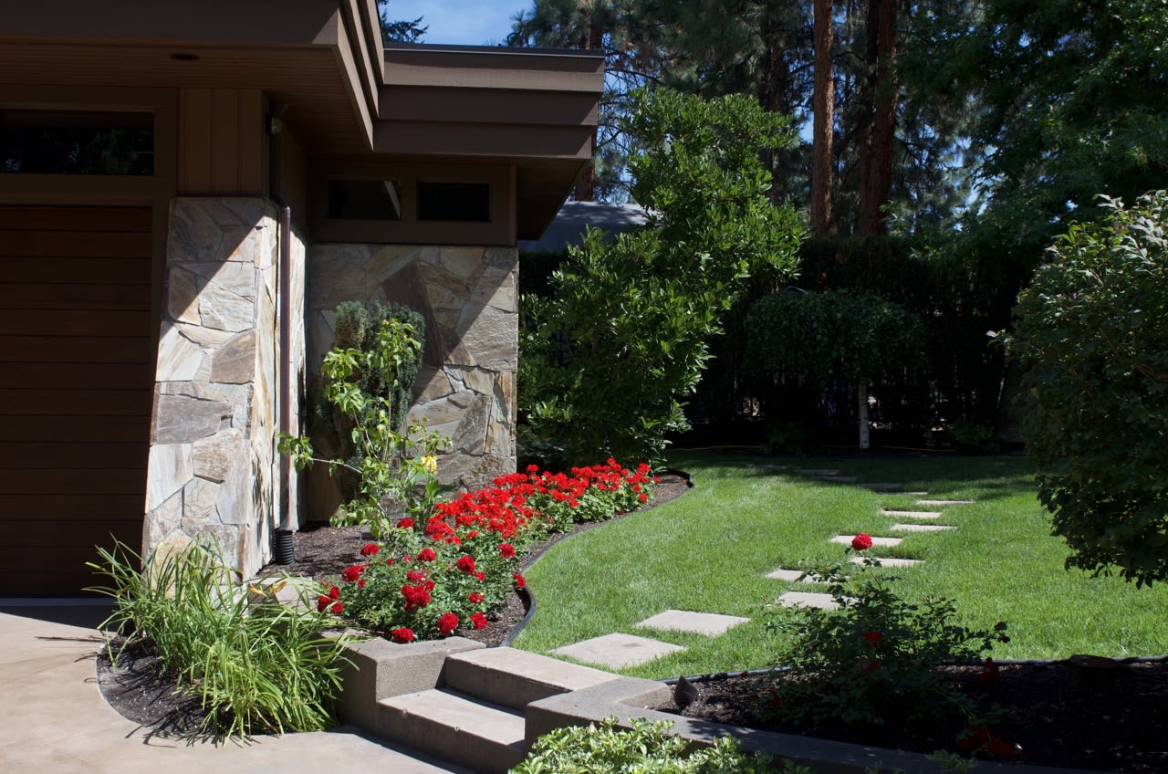 Lush outdoor plants, a handcrafted retaining wall, and a relaxing walkway showcase the harmony of function and form in this Kelowna yard.